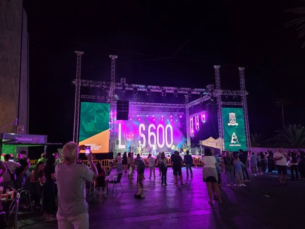 Concierto en Adeje Escenario de un concierto nocturno en Adeje durante las fiestas patronales de 2025, con público delante y luces de colores iluminando la plaza.