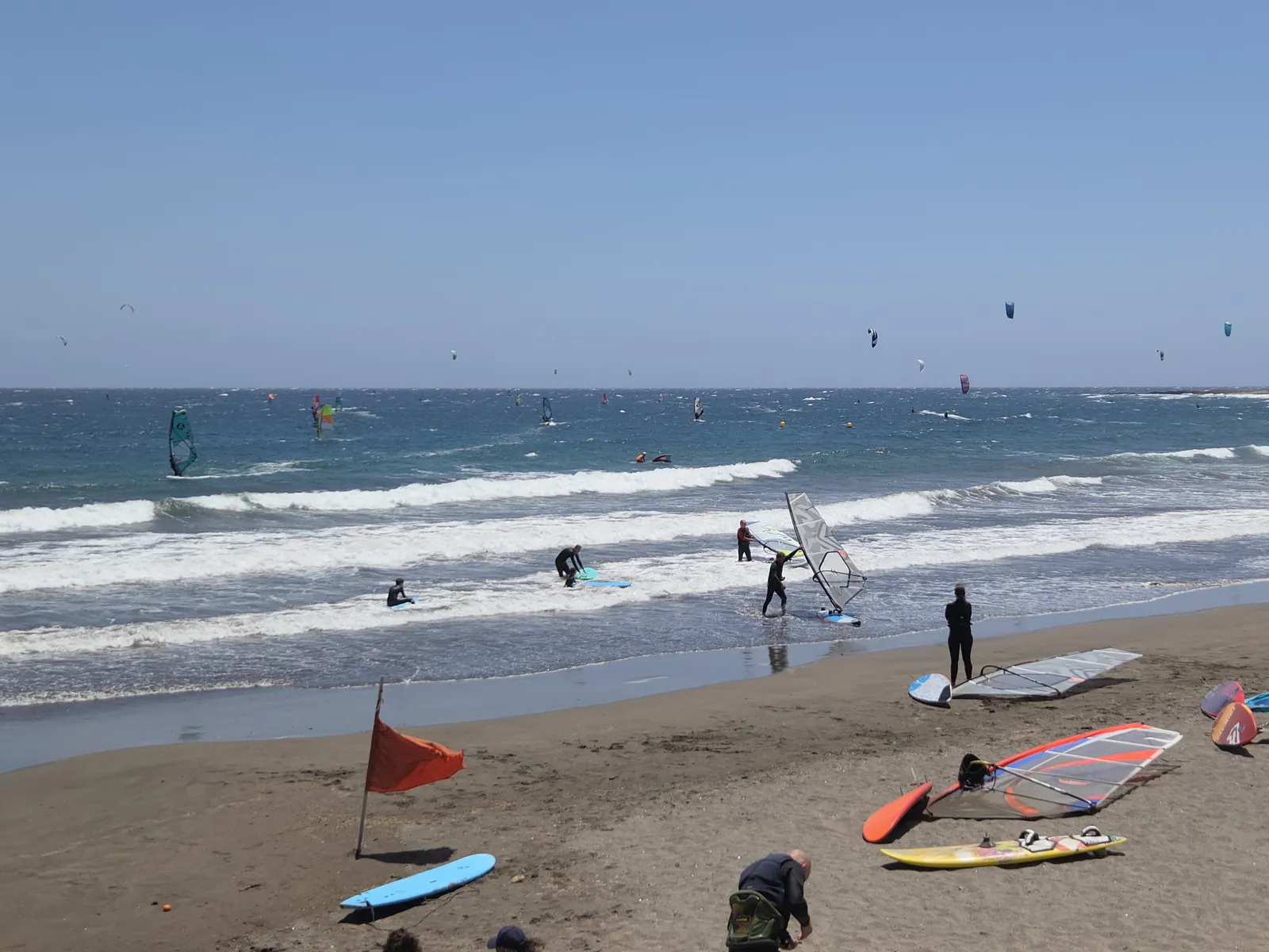 El Médano, zona de windsurf, kitesurf y paddle surf en Tenerife Windsurfistas y kitesurfistas en la bahía de El Médano durante un día ventoso